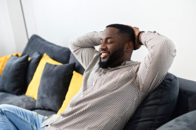 Relaxed,Young,African,Man,Resting,On,Comfortable,Couch,Holding,Hands